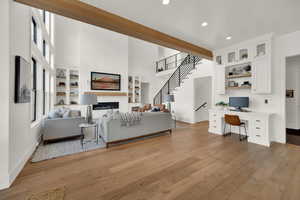 Living area featuring built in desk, a large fireplace, recessed lighting, light wood finished floors, and stairway