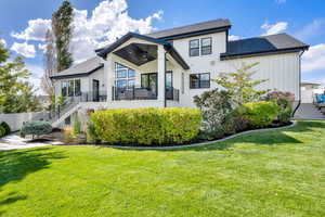 Back of property with stairway, a yard, a shingled roof, and a balcony