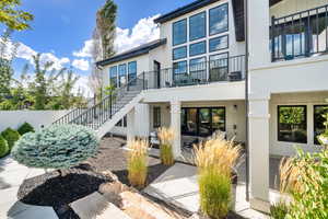 Rear view of house with stairs, a balcony, a patio area, and board and batten siding