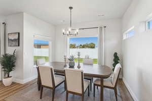 Dining space featuring healthy amount of natural light, wood finished floors, and a chandelier