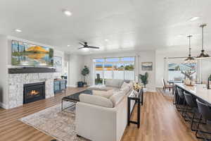 Living area featuring light wood-style floors, a textured ceiling, a fireplace, recessed lighting, and ceiling fan