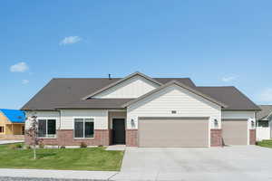 View of front of property with concrete driveway, a front yard, brick siding, board and batten siding, and a garage