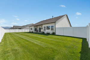 Rear view of property with a fenced backyard and a patio area