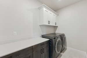 Laundry area featuring independent washer and dryer, light tile patterned flooring, and cabinet space