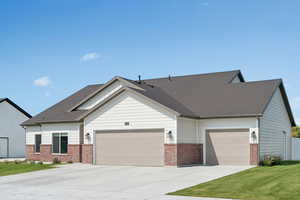 View of front facade featuring brick siding, a garage, concrete driveway, and a front yard