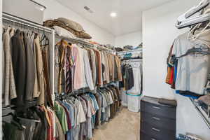 Walk in closet with light carpet and a wall unit AC