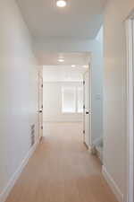 Corridor with light wood-style floors and recessed lighting