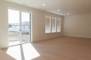 Empty room with light wood finished floors and recessed lighting