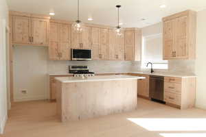 Kitchen featuring light brown cabinets, backsplash, decorative light fixtures, appliances with stainless steel finishes, and recessed lighting