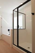 Full bath featuring a shower stall, recessed lighting, a bath, and light wood-style floors