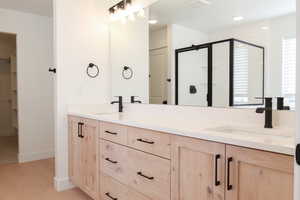 Bathroom featuring a walk in closet, double vanity, a shower stall, light wood finished floors, and recessed lighting