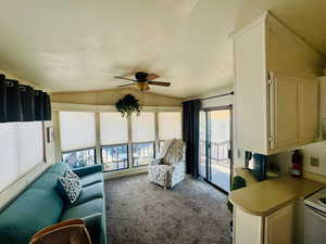 Carpeted living area featuring lofted ceiling and a ceiling fan