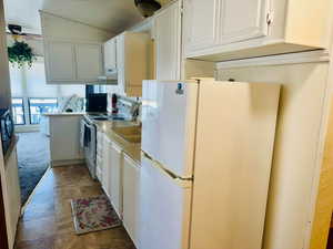 Kitchen with white appliances, white cabinetry, light countertops, and extractor fan
