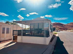 View of property exterior with a sunroom and a deck with mountain view