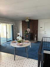 Carpeted living room with a wood stove, a textured ceiling, and a ceiling fan