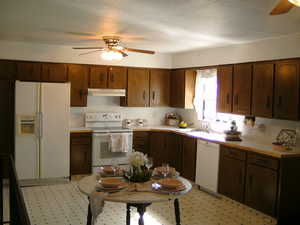 Kitchen featuring a ceiling fan, white appliances, light countertops, under cabinet range hood, and light floors