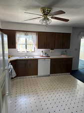 Kitchen with a textured ceiling, light countertops, dark brown cabinets, white appliances, and ceiling fan