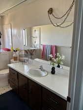 Bathroom with vanity, wallpapered walls, and light tile patterned flooring