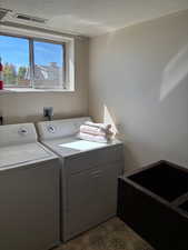 Washroom with washer and dryer and a textured ceiling