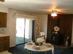 Dining area with a wood stove, ceiling fan, and light carpet