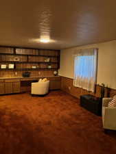 Sitting room featuring wood walls, a wainscoted wall, dark carpet, and a textured ceiling