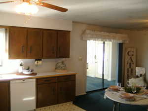 Kitchen featuring ceiling fan, light countertops, dishwasher, and brown cabinets
