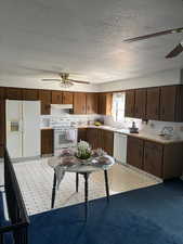 Kitchen featuring ceiling fan, white appliances, light countertops, a textured ceiling, and under cabinet range hood