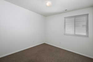 Unfurnished room featuring dark carpet and baseboards