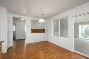 Unfurnished dining area with dark wood-style floors and baseboards
