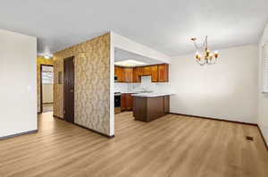 Kitchen with light countertops, plenty of natural light, brown cabinetry, a peninsula, and a textured ceiling
