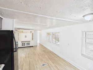 Unfurnished living room with light wood-style floors and a textured ceiling