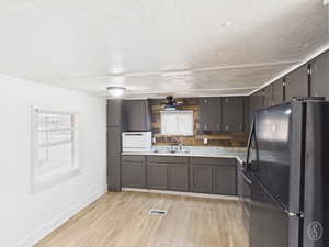 Kitchen featuring freestanding refrigerator, light wood-style floors, and a textured ceiling
