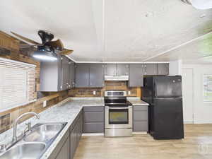 Kitchen with decorative backsplash, stainless steel range with electric cooktop, freestanding refrigerator, light countertops, and light wood-type flooring