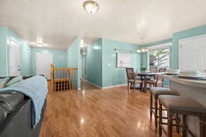 Living area with light wood-type flooring, a textured ceiling, and a chandelier