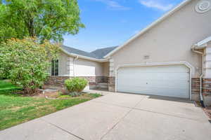 View of front of property featuring stucco siding, stone siding, and driveway