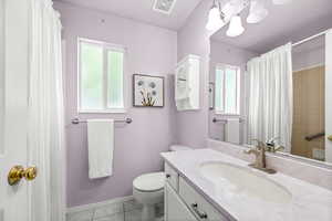 Full bathroom with light tile patterned floors, vanity, plenty of natural light, and a shower with curtain