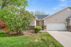View of front facade with a garage, stucco siding, driveway, a shingled roof, and a front yard