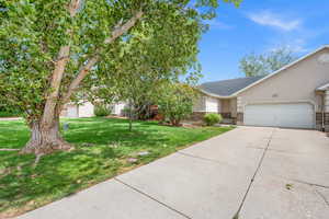 View of front of house featuring a front yard, concrete driveway, stucco siding, and an attached garage