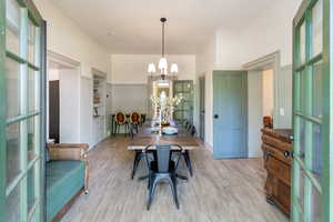 Dining room featuring wood finished floors, a chandelier, and wainscoting