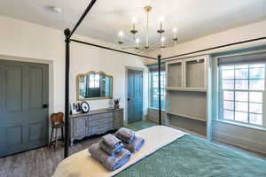 Bedroom with multiple windows, wood finished floors, a textured ceiling, and a chandelier