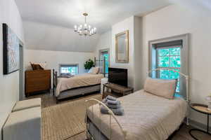 Bedroom featuring lofted ceiling, wood finished floors, and a chandelier