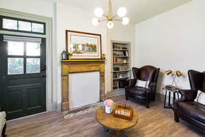 Living area featuring wood finished floors, a chandelier, and built in shelves