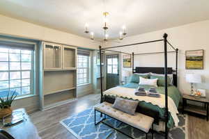 Bedroom with a textured ceiling, wood finished floors, and a chandelier
