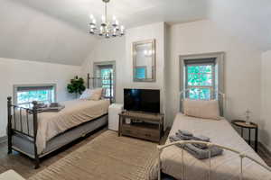 Bedroom with vaulted ceiling, wood finished floors, and a chandelier