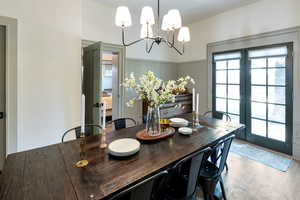 Dining space featuring a chandelier, french doors, wood finished floors, and wainscoting