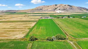 Aerial view of property and surrounding area with a mountain backdrop, rural landscape, and extensive farmland