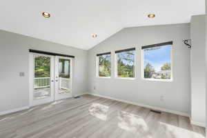 Empty room featuring recessed lighting, lofted ceiling, light wood-type flooring, and french doors