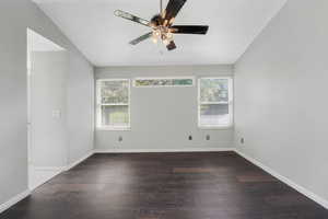 Empty room featuring dark wood-style floors, lofted ceiling, and ceiling fan