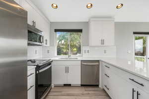 Kitchen featuring stainless steel appliances, recessed lighting, white cabinetry, healthy amount of natural light, and light wood-style floors