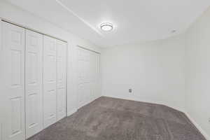 Unfurnished bedroom featuring dark colored carpet and two closets